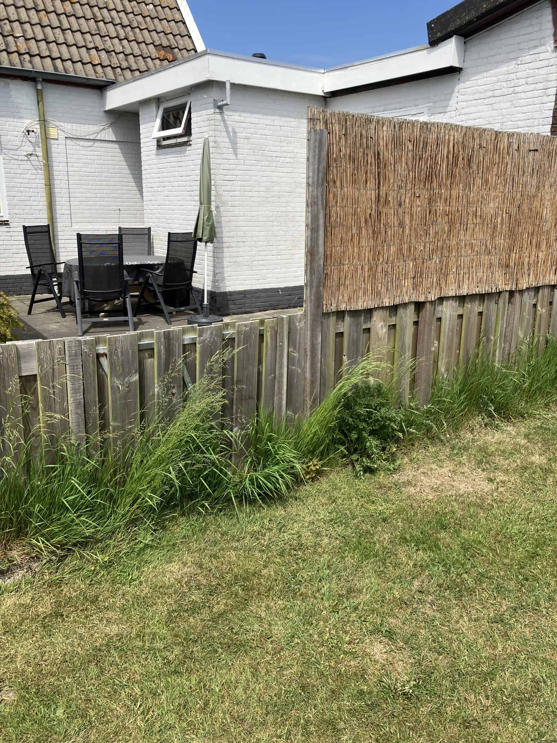 Het terras naast de vakantiewoning met tafel, stoelen en parasol